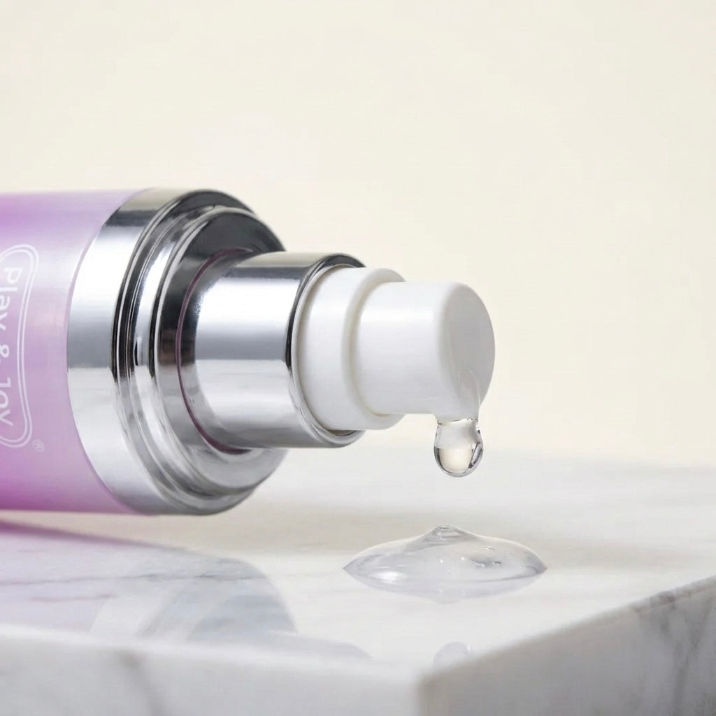 Primer plano del dosificador plateado mostrando la textura del suero transparente de las Gotas Íntimas Sensibilizantes cayendo sobre mármol.