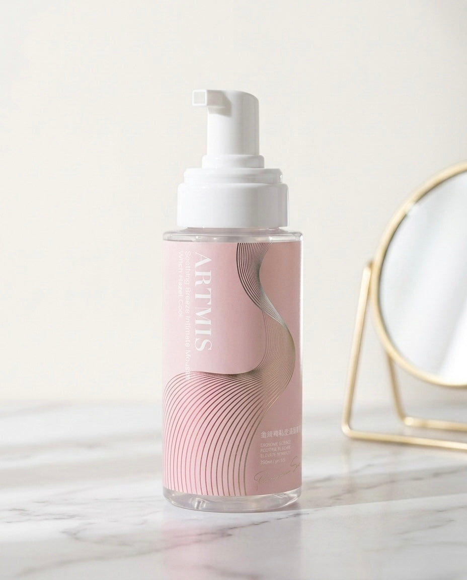 Mousse Limpiadora Íntima con Hamamelis sobre superficie de mármol blanco con espejo dorado decorativo