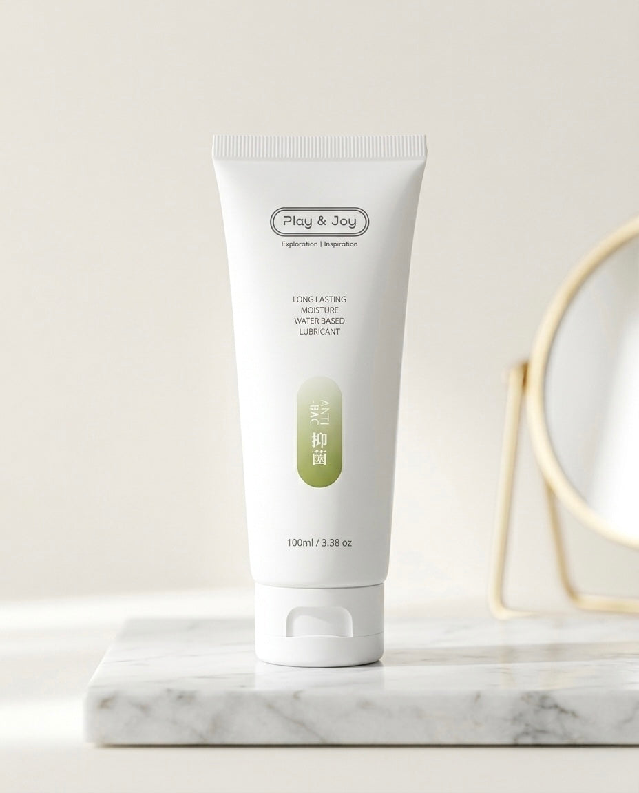 Primer plano del Lubricante Íntimo Antibacteriano sobre una superficie de mármol blanco, con un espejo dorado de fondo decorativo.